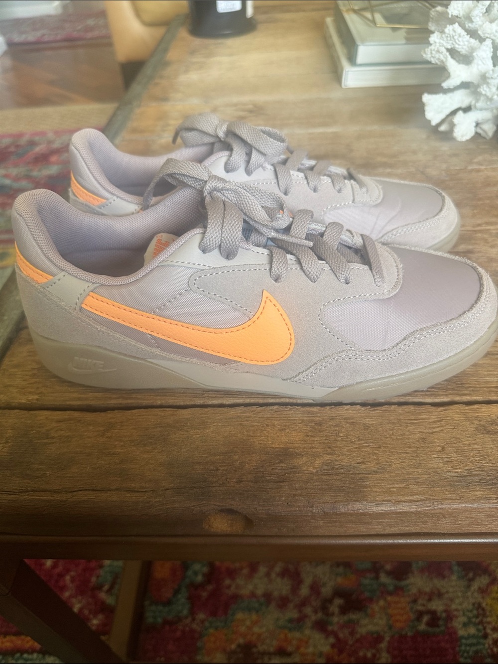 Nike Womenโs Gray Sneakers with Orange Swoosh Accent